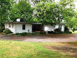 Magnolia before renovation -- white stucco house with damaged flat roof