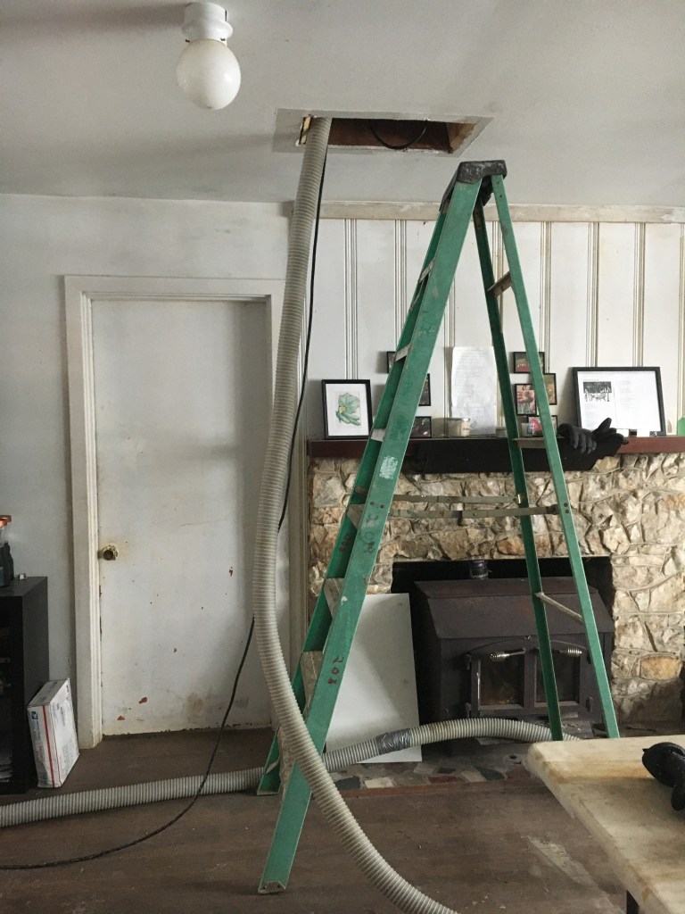 Hose from blower wrapping up ladder to where Alexis is blowing insulation in the attic