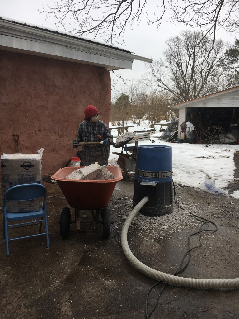 Debbie shoveling insulation into the blower