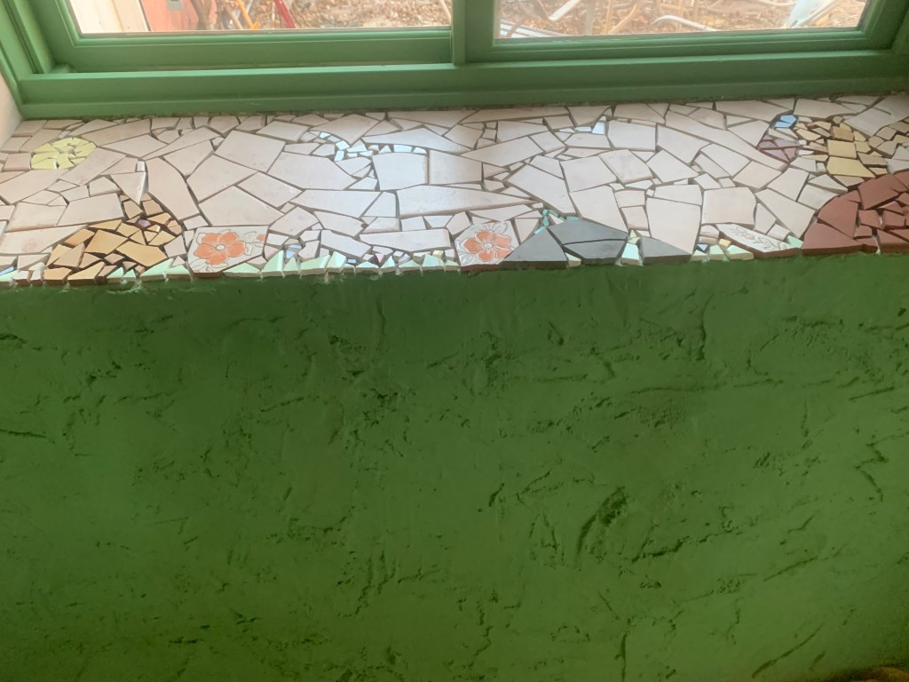 Mosaic windowsill of newest bedroom, with a rabbit, flowers, squirrel, birds, and other animals